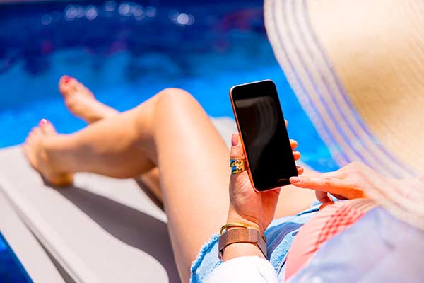 Pool service customer relaxing poolside and checking the upcoming service visit on a mobile app — the user experience EZ Pool Biller delivers